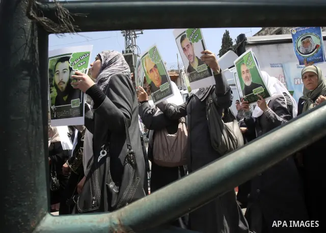 Palestinian woman stands near portraits for prisoners jailed in Israel during a demonstration calling for their release, in the West Bank city of Nablus on April 25, 2012. Photo by Wagdi Eshtayah