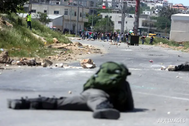 An Israeli soldier fires rubber bullets at Palestinian protesters during clashes at the Bitwonia crossing outside the Israeli military prison of Ofer, on Israel's 64th Independence Day, 26 April 2012. Palestinians staged...