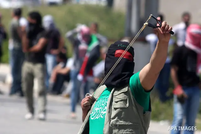 Palestinians hurl stones at an Israeli jeep during clashes with Israeli soldiers at the Bitwonia crossing outside the Israeli military prison of Ofer, on Israel's 64th Independence Day, 26 April 2012. Palestinians staged...