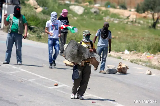 Palestinians hurl stones at an Israeli jeep during clashes with Israeli soldiers at the Bitwonia crossing outside the Israeli military prison of Ofer, on Israel's 64th Independence Day, 26 April 2012. Palestinians staged...