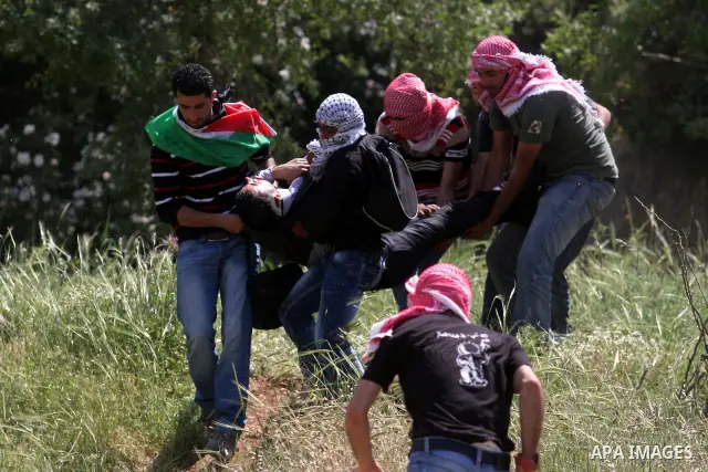 Palestinians carry a wounded demonstrator injured during clashes with Israeli soldiers at the Bitwonia crossing outside the Israeli military prison of Ofer, on Israel's 64th Independence Day, 26 April 2012. Palestinians...