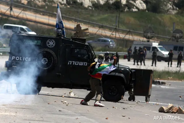 Palestinians hurl stones at an Israeli jeep during clashes with Israeli soldiers at the Bitwonia crossing outside the Israeli military prison of Ofer, on Israel's 64th Independence Day, 26 April 2012. Palestinians staged...
