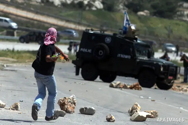 Palestinians hurl stones at an Israeli jeep during clashes with Israeli soldiers at the Bitwonia crossing outside the Israeli military prison of Ofer, on Israel's 64th Independence Day, 26 April 2012. Palestinians staged...