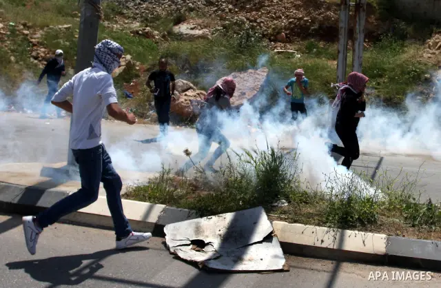 Palestinians hurl stones at an Israeli jeep during clashes with Israeli soldiers at the Bitwonia crossing outside the Israeli military prison of Ofer, on Israel's 64th Independence Day, 26 April 2012. Palestinians staged...