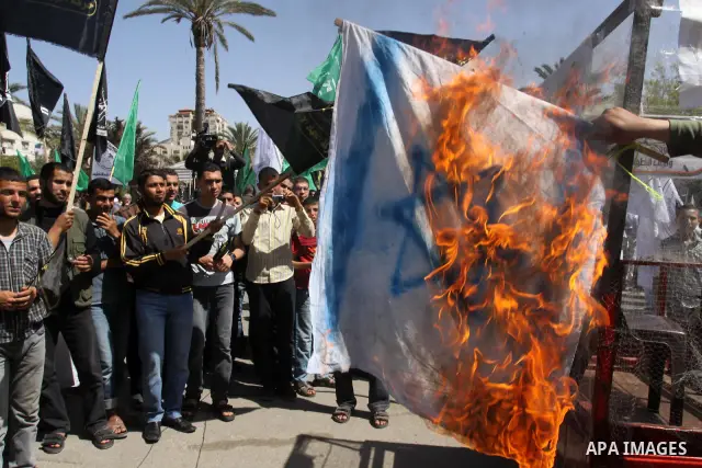 Palestinian protesters burn israeli flag, and hold up banners and portraits during a protest to call for the release of Palestinian prisoners held in Israeli jails in Gaza City on April 27, 2012. Some 1,600 Palestinian p...