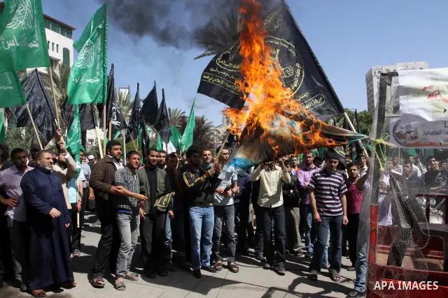 Palestinian protesters burn israeli flag, and hold up banners and portraits during a protest to call for the release of Palestinian prisoners held in Israeli jails in Gaza City on April 27, 2012. Some 1,600 Palestinian p...
