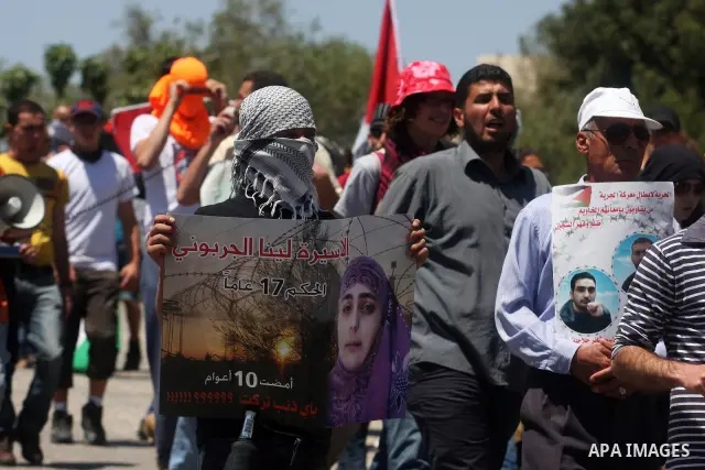 Palestinian protesters hold up banners and portraits during a protest to call for the release of Palestinian prisoners held in Israeli jails in the West Bank village of Nabi Saleh near Ramallah, on April 27, 2012. Photo...