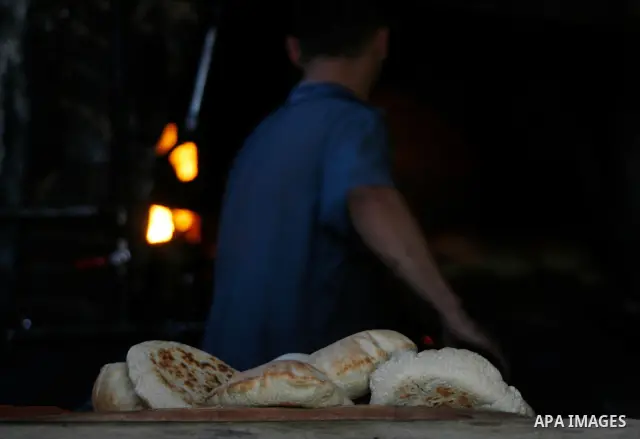 A Palestinian man bakes loaves of bread in a traditional mud oven in Rafah refugee camp, southern Gaza Strip on April 28, 2012. Photo by Eyad Al Baba