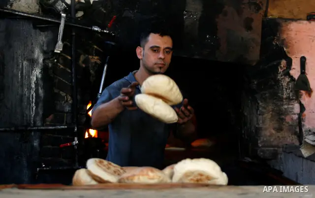 A Palestinian man bakes loaves of bread in a traditional mud oven in Rafah refugee camp, southern Gaza Strip on April 28, 2012. Photo by Eyad Al Baba