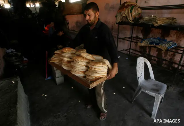 A Palestinian man bakes loaves of bread in a traditional mud oven in Rafah refugee camp, southern Gaza Strip on April 28, 2012. Photo by Eyad Al Baba