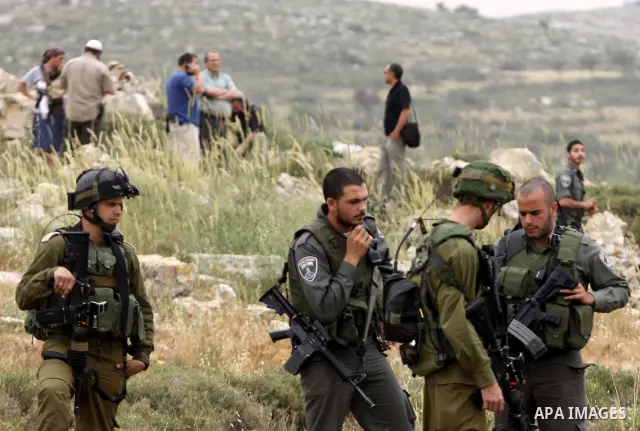 Israeli soldiers stand between Palestinian farmers and jewish settlers after clashes in Qusra village near the west bank city of Nablus, on April 29, 2012. Photo by Nedal Shtieh