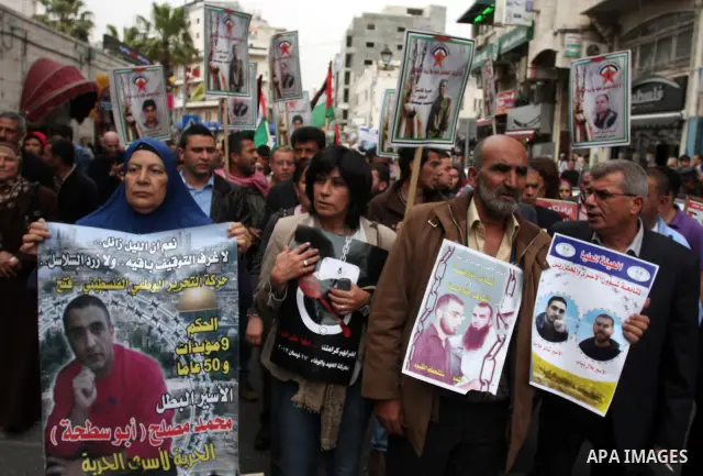 Palestinian protesters hold up banners and portraits of a prisoners jailed in Israel,during a rally in solidarity with prisoners in Israeli jails, in the West Bank city of Ramallah, April 29, 2012.Over the past week, ove...