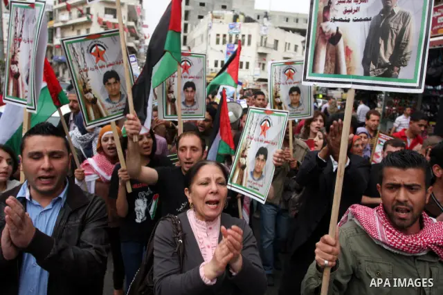 Palestinian protesters hold up banners and portraits of a prisoners jailed in Israel,during a rally in solidarity with prisoners in Israeli jails, in the West Bank city of Ramallah, April 29, 2012.Over the past week, ove...