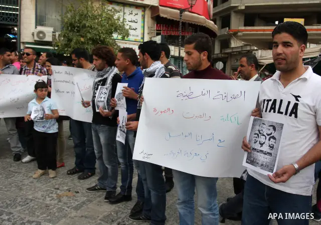 Palestinian journalists hold up banners and portraits of a prisoners jailed in Israel,during a rally in solidarity with prisoners in Israeli jails, in the West Bank city of Ramallah, April 29, 2012.Over the past week, ov...
