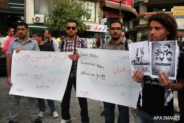 Palestinian journalists hold up banners and portraits of a prisoners jailed in Israel,during a rally in solidarity with prisoners in Israeli jails, in the West Bank city of Ramallah, April 29, 2012.Over the past week, ov...