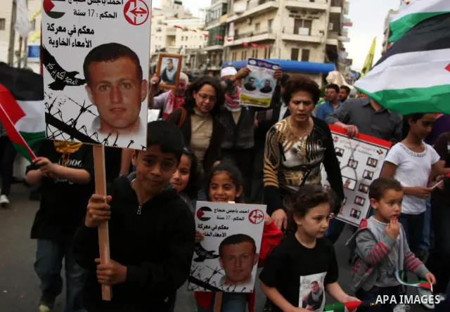 Palestinian protesters hold up banners and portraits of a prisoners jailed in Israel,during a rally in solidarity with prisoners in Israeli jails, in the West Bank city of Ramallah, April 30, 2012. Over the past week, ov...