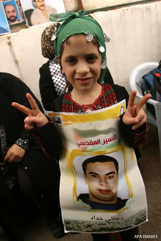 Palestinian child holds up banners and portraits of a prisoners jailed in Israel, during a Sit-in held in the neighborhood of Sheikh Jarrah, in front of the Red Cross in the West Bank city of Jerusalem, April 30, 2012. O...