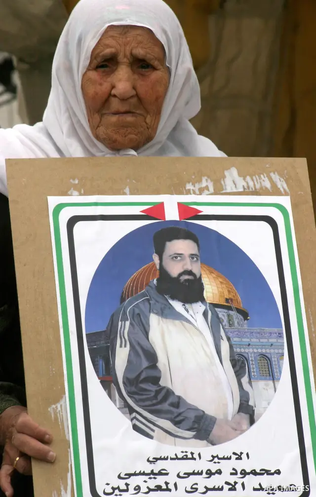 Palestinian old woman holds up banners and portraits of a prisoners jailed in Israel, during a Sit-in held in the neighborhood of Sheikh Jarrah, in front of the Red Cross in the West Bank city of Jerusalem, April 30, 201...