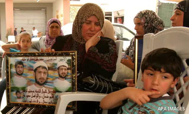 Palestinian protesters hold up banners and portraits of a prisoners jailed in Israel, during a Sit-in held in the neighborhood of Sheikh Jarrah, in front of the Red Cross in the West Bank city of Jerusalem, April 30, 201...