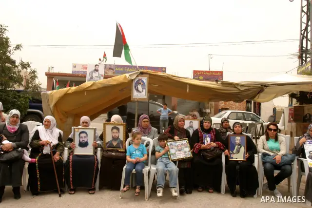 Palestinian protesters hold up banners and portraits of a prisoners jailed in Israel, during a Sit-in held in the neighborhood of Sheikh Jarrah, in front of the Red Cross in the West Bank city of Jerusalem, April 30, 201...