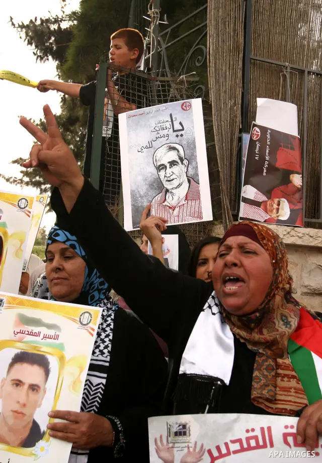 Palestinian protesters hold up banners and portraits of a prisoners jailed in Israel, during a Sit-in held in the neighborhood of Sheikh Jarrah, in front of the Red Cross in the West Bank city of Jerusalem, April 30, 201...