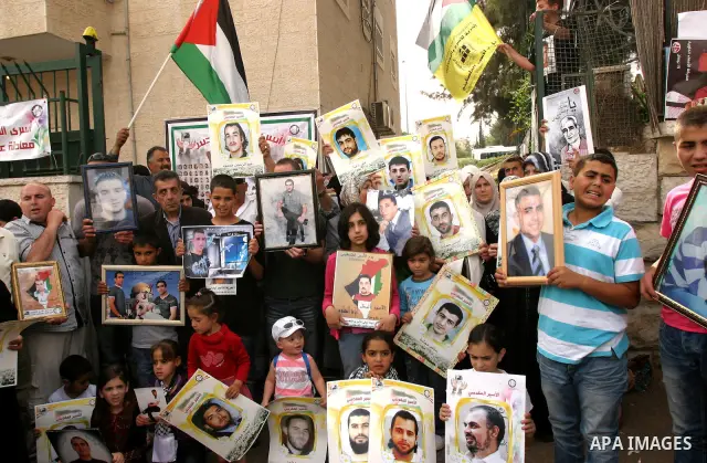 Palestinian protesters hold up banners and portraits of a prisoners jailed in Israel, during a Sit-in held in the neighborhood of Sheikh Jarrah, in front of the Red Cross in the West Bank city of Jerusalem, April 30, 201...