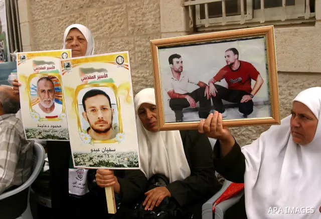 Palestinian protesters hold up banners and portraits of a prisoners jailed in Israel, during a Sit-in held in the neighborhood of Sheikh Jarrah, in front of the Red Cross in the West Bank city of Jerusalem, April 30, 201...