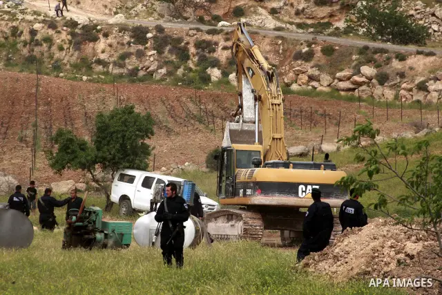 Israeli soldiers surround a bulldozer as it destroys a Palestinian farm to cows in the West Bank city of Hebron, May. 01, 2012. Reports state that tensions rose as Palestinian homes were destroyed by Israeli authorities...