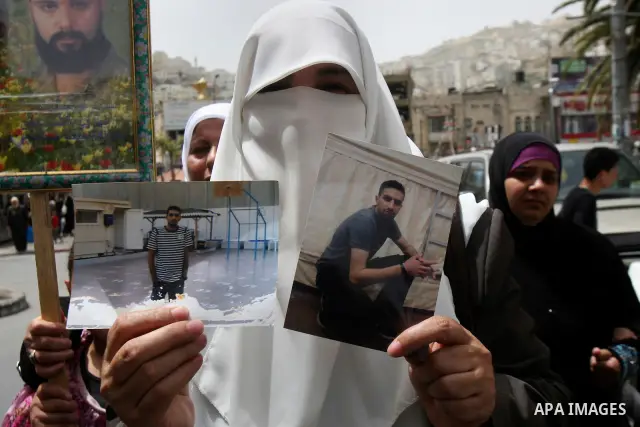 Palestinian protesters hold up banners and portraits of a prisoners jailed in Israel, during a demonstration in the West Bank city of Nablus, May 1, 2012. Over the past week, over 1,350 Palestinian prisoners have begun a...
