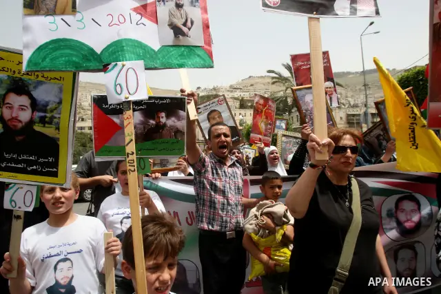 Palestinian protesters hold up banners and portraits of a prisoners jailed in Israel, during a demonstration in the West Bank city of Nablus, May 1, 2012. Over the past week, over 1,350 Palestinian prisoners have begun a...