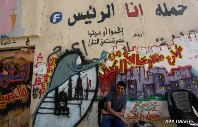 Egyptian youth sets in front of graffiti on a wall in Tahrir Square in Cairo on May 01, 2012. Egyptians demanded that their military rulers pledge to hand over power by mid-year after a row over who can run in the presid...