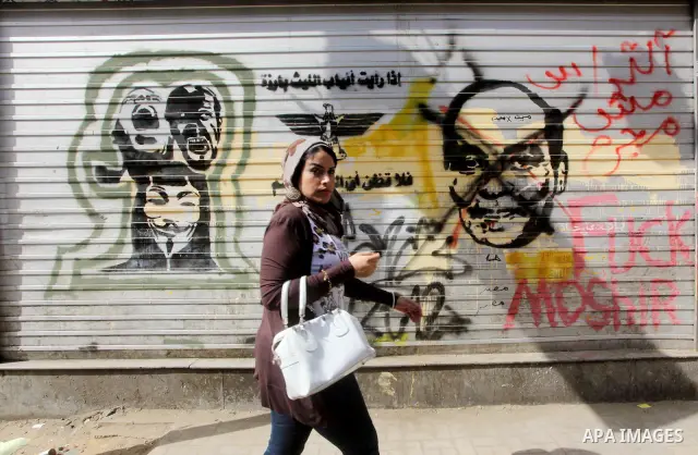 Egyptian girl walks in front of graffiti on a wall in Tahrir Square in Cairo on May 01, 2012. Egyptians demanded that their military rulers pledge to hand over power by mid-year after a row over who can run in the presid...