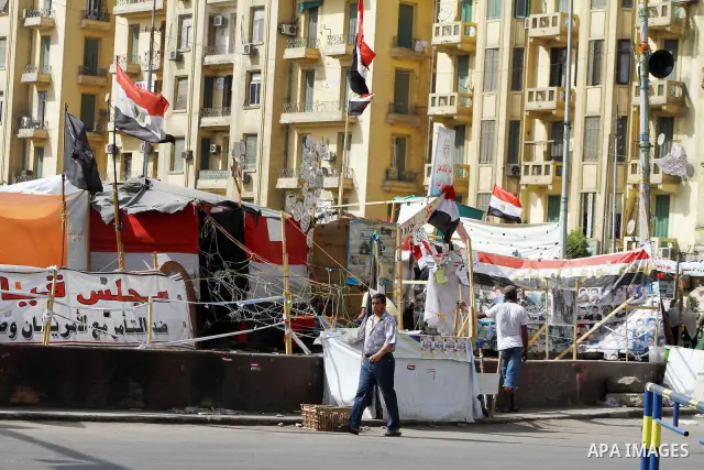 Egyptians people walk in front of portraits and national flags at Tahrir Square in Cairo May 01, 2012. Egyptians demanded that their military rulers pledge to hand over power by mid-year after a row over who can run in t...