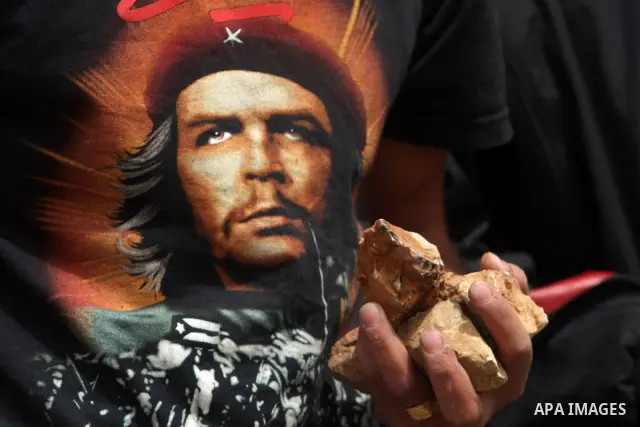 A Palestinian protester, wearing a T-shirt bearing a portrait of Che Guevara, carries stones during clashes with Israeli troops outside Ofer military prison near the West Bank city of Ramallah on May 1, 2012, following a...