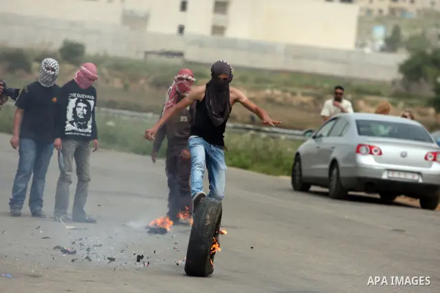 Protesters light a rubber tyre and kick it towards a fence during a demonstration outside Ofer military prison near the West Bank city of Ramallah on May 1, 2012 in a show of support for prisoners held in Israeli jails....
