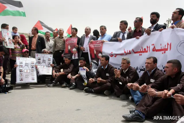 Palestinian protesters gesture with their hands chained during a protest outside Ofer prison near the West Bank city of Ramallah May 1, 2012, in solidarity with hunger striking Palestinian prisoners. The hunger strike ag...