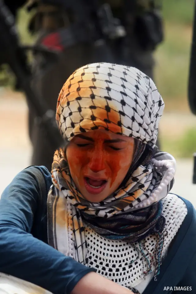 A demonstrator grimaces after she was pepper sprayed by Israeli troops during a protest calling for the release prisoners jailed in Israel outside the Ofer military prison, near the West Bank city of Ramallah on May 1, 2...