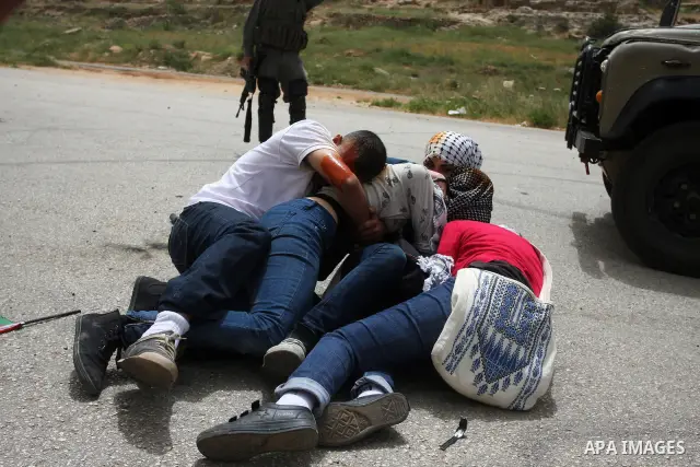 Palestinian protesters who were hit with pepper spray by Israeli border police, lie on the ground as they try to prevent Israeli troops from detaining one of them, during clashes outside Ofer prison near the West Bank ci...