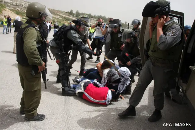 Palestinian protesters who were hit with pepper spray by Israeli border police, lie on the ground as they try to prevent Israeli troops from detaining one of them, during clashes outside Ofer prison near the West Bank ci...
