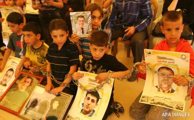 Palestinian children hold up banners and portraits of a prisoners jailed in Israel, during a Sit-in held in the West Bank city of Jerusalem, May 01, 2012. Over the past week, over 1,350 Palestinian prisoners have begun a...