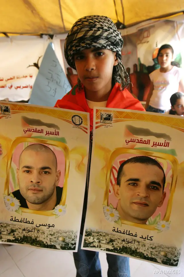 Palestinian child holds up banners and portraits of a prisoners jailed in Israel, during a Sit-in held in the West Bank city of Jerusalem, May 01, 2012. Over the past week, over 1,350 Palestinian prisoners have begun an...