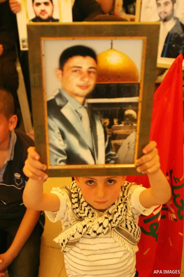 Palestinian child holds up banners and portraits of a prisoners jailed in Israel, during a Sit-in held in the West Bank city of Jerusalem, May 01, 2012. Over the past week, over 1,350 Palestinian prisoners have begun an...
