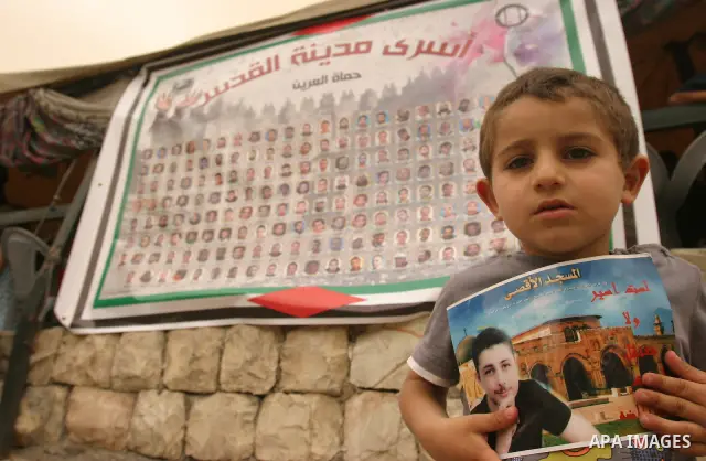 Palestinian child holds up banners and portraits of a prisoners jailed in Israel, during a Sit-in held in the West Bank city of Jerusalem, May 01, 2012. Over the past week, over 1,350 Palestinian prisoners have begun an...