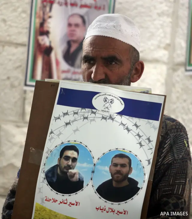 Palestinian Old man holds up portrait of a prisoners jailed in Israel,during a rally in solidarity with prisoners in Israeli jails,outside the Red Cross building in the West Bank city of Ramallah on May 1, 2012. Photo by...