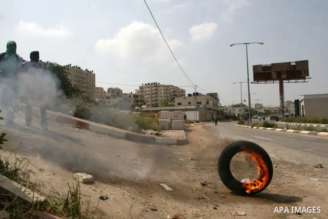A Palestinian protester kicks a burning tire towards Israeli troops during clashes next to the Israeli military prison of Ofer, near Beitunia, West Bank, 03 May 2012. following a demonstration in solidarity with Palestin...