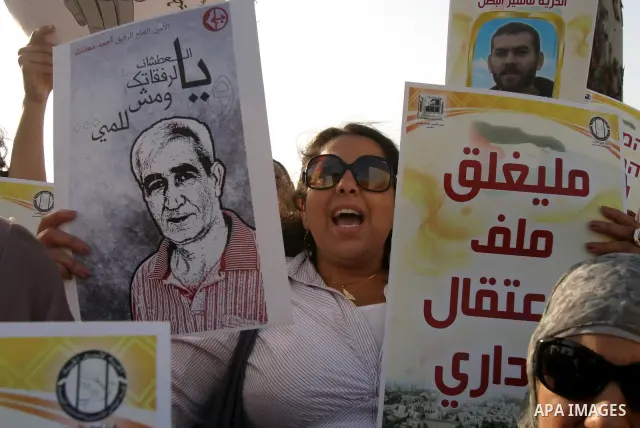 Palestinian protesters hold up banners and portraits of a prisoners jailed in Israel, during a rally next to Al-Ramle Prison, near Tel Aviv, Thursday, May 3, 2012. A Palestinian rights group said recently that half of ab...