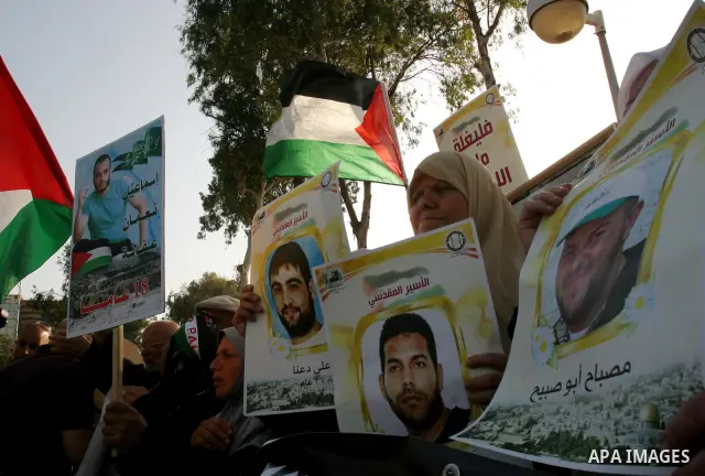 Palestinian protesters hold up banners and portraits of a prisoners jailed in Israel, during a rally next to Al-Ramle Prison, near Tel Aviv, Thursday, May 3, 2012. A Palestinian rights group said recently that half of ab...