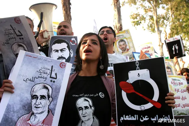Palestinian protesters hold up banners and portraits of a prisoners jailed in Israel, during a rally next to Al-Ramle Prison, near Tel Aviv, Thursday, May 3, 2012. A Palestinian rights group said recently that half of ab...