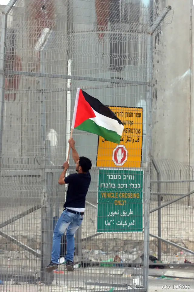 A Palestinian man hold national flag at the Qalandia crossing in the occupied West Bank during a demonstration on May 4, 2012 in solidarity with Palestinian prisoners on hunger strike to protest Israel's use of administr...