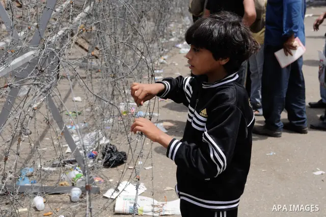 May 4, 2012 - Cairo, Egypt - An Egyptian boy looks at the army line through the barbed wire defenses during the 'Final Friday' protests against Military Rule in the Abasseya neighborhood of Cairo on May 4, 2012. The 'Fin...